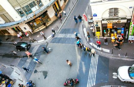 Busy street scene near Duo Hotel, a most-booked gay hotel in Paris near gay bars and saunas. View from above of people, cars, and cafes.