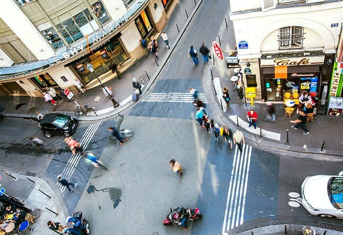 Busy street scene near Duo Hotel, a most-booked gay hotel in Paris near gay bars and saunas. View from above of people, cars, and cafes.
