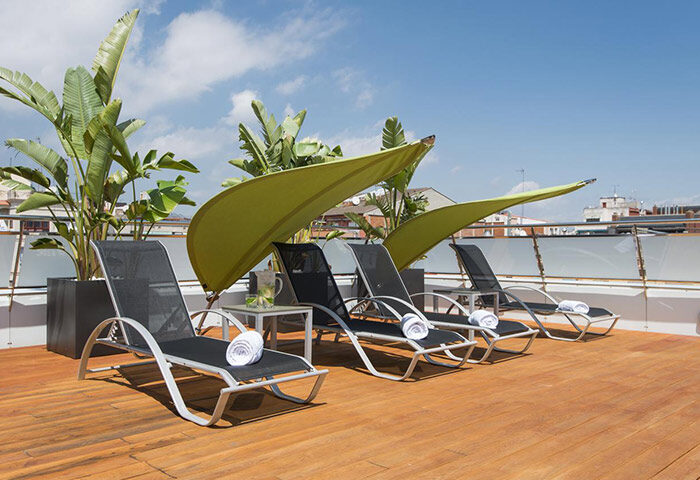 Ako Suites Hotel rooftop terrace with lounge chairs and sunshades. Most-booked gay hotel serviced apartment in Barcelona's gayborhood.