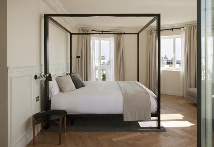 Dear Hotel Madrid room: A most-booked gay hotel in Madrid for gay couples. Bedroom with four-poster bed, neutral decor, and city views.