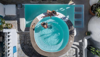 Carbonaki Hotel, Mykonos Town: Aerial view of a couple relaxing by the pool. Most booked gay hotel in Mykonos, perfect for gay travel.