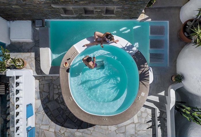 Carbonaki Hotel, Mykonos Town: Aerial view of a couple relaxing by the pool. Most booked gay hotel in Mykonos, perfect for gay travel.