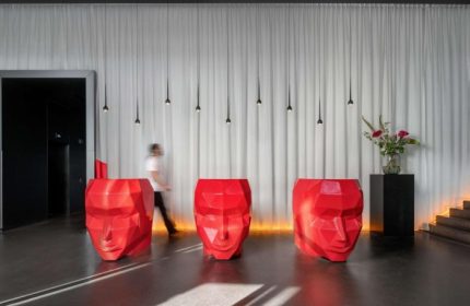 Art'otel Amsterdam lobby. Red geometric face sculptures serve as reception desks. Modern, stylish design for gay travelers in Amsterdam.