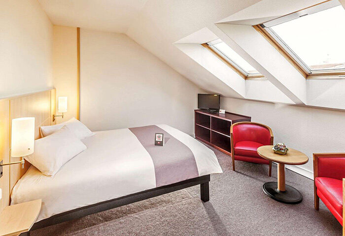 Ibis Praha Wenceslas Square Hotel room. Gay-friendly Prague hotel with skylights, bed, TV, and red chairs. Great location near gayborhood.