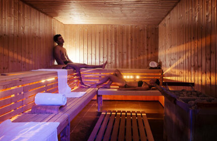Sauna at NH Collection Carlo IV, a most-booked gay hotel in Prague Old Town. Man and woman relaxing in the wooden sauna.