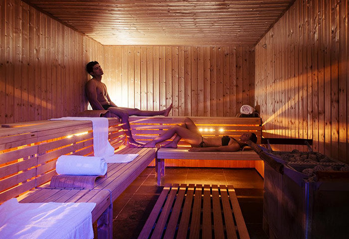 Sauna at NH Collection Carlo IV, a most-booked gay hotel in Prague Old Town. Man and woman relaxing in the wooden sauna.