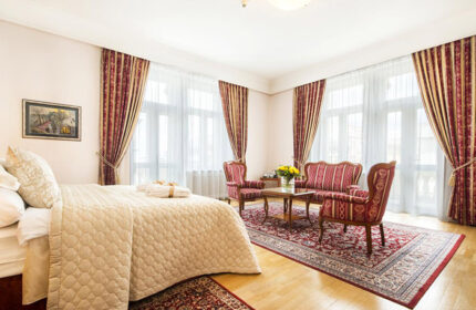 Boutique Hotel Seven Days room in Prague's gay hub, Vinohrady. Elegant interior with a bed, seating area, and traditional decor. Most booked gay hotels.