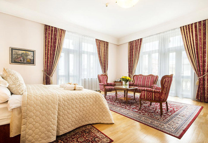 Boutique Hotel Seven Days room in Prague's gay hub, Vinohrady. Elegant interior with a bed, seating area, and traditional decor. Most booked gay hotels.