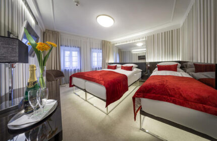 Hotel Clementin Old Town triple room for gay travelers in Prague. Modern design, red accents, champagne, and flowers await.