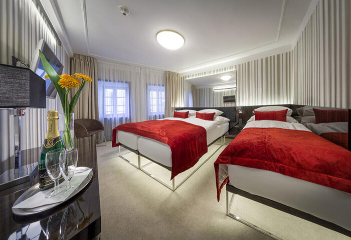 Hotel Clementin Old Town triple room for gay travelers in Prague. Modern design, red accents, champagne, and flowers await.