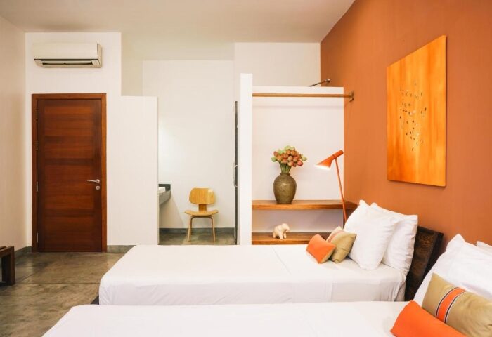 Rambutan Resort, Phnom Penh: Modern room with twin beds, orange accents, and minimalist decor. Gay-friendly hotel in Phnom Penh City Center.