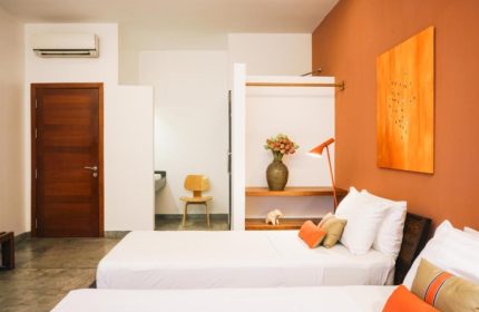 Rambutan Resort, Phnom Penh: Modern room with twin beds, orange accents, and minimalist decor. Gay-friendly hotel in Phnom Penh City Center.