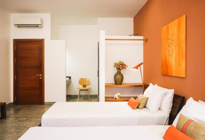 Rambutan Resort, Phnom Penh: Modern room with twin beds, orange accents, and minimalist decor. Gay-friendly hotel in Phnom Penh City Center.