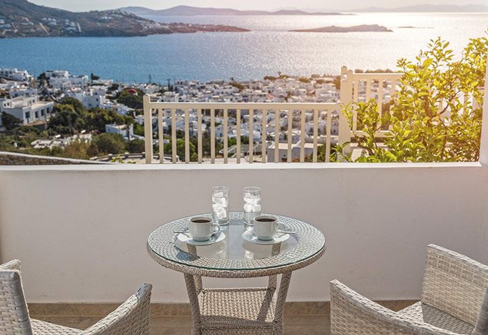 Hotel Alkyon, Mykonos Town balcony view. Coffee & drinks on table. Gay-friendly location with sea view. Most booked hotel.