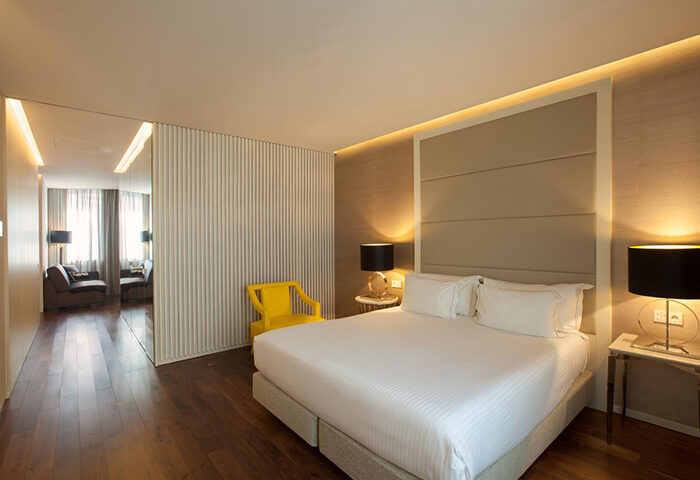 BessaHotel Liberdade Lisbon room. Modern gay luxury hotel bedroom with king bed, yellow chair, wood floors. Most booked hotels for gay men.