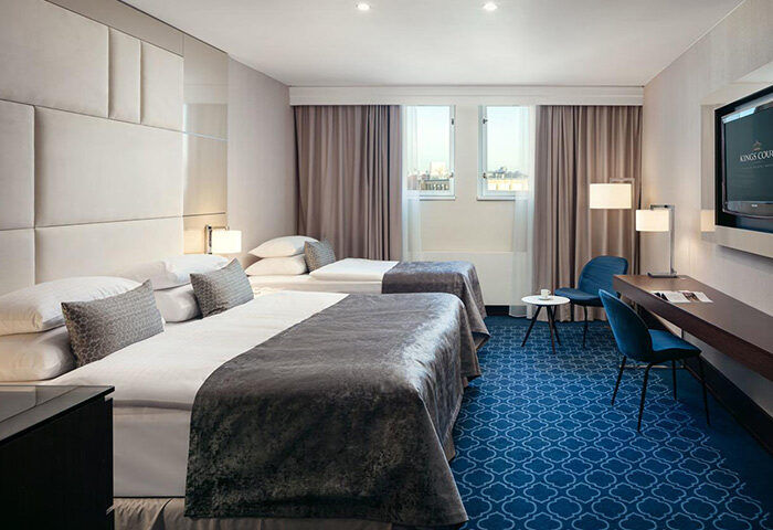 Hotel Kings Court, Prague: Luxury room for three persons in Old Town. Most booked gay hotel with two beds, blue carpet, desk, and chairs.