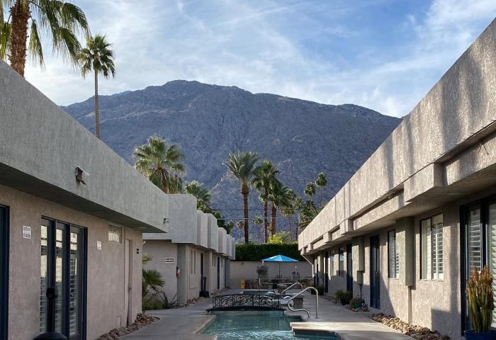 All Worlds Resorts, a gay men's clothing optional resort in Palm Springs, CA. Pool view with mountain backdrop. Most-booked gay hotel.