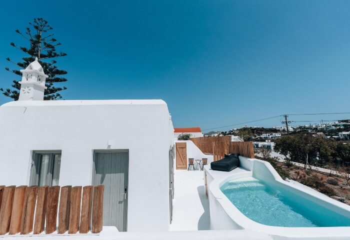 Akkadian Gay Only Hotel Mykonos pool villa. White building, blue sky, and pool. Most-booked gay hotel in Mykonos for gay men's travel.