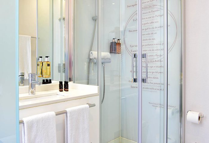 My Story Hotel Ouro's bathroom in Lisbon. A most-booked honeymoon gay hotel. Shower with Portuguese quotes, sink, and towels. Gay travel.