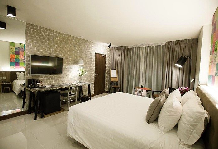 Art Mai Gallery Nimman Hotel Chiang Mai room. LGBT luxury stay with brick wall, desk, TV, and bright, modern design. Most booked hotel.
