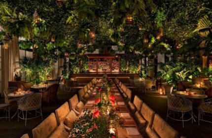 The Times Square EDITION Hotel's lush, gay-friendly restaurant. Tropical plants, lanterns, and a long table create a unique dining experience.