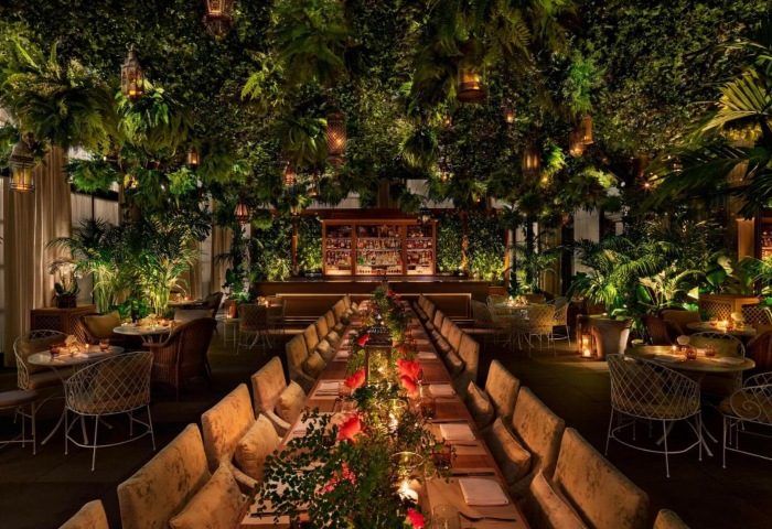The Times Square EDITION Hotel's lush, gay-friendly restaurant. Tropical plants, lanterns, and a long table create a unique dining experience.