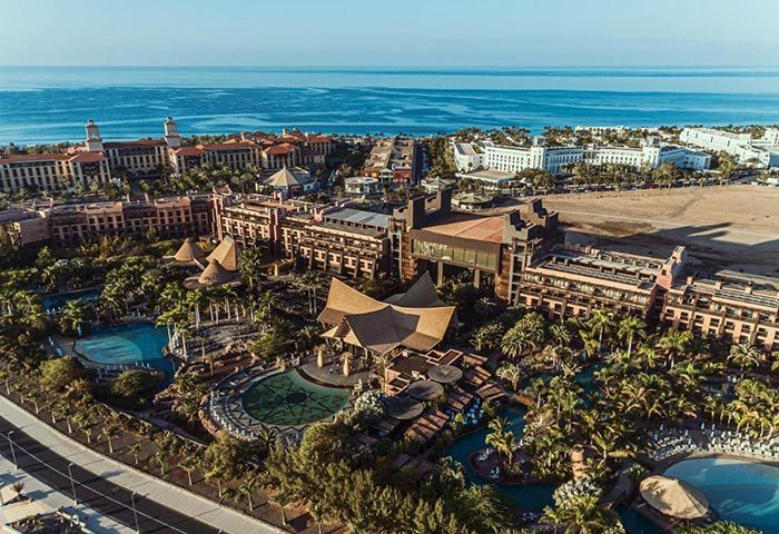 Lopesan Baobab Resort aerial view. Most booked luxury gay hotel in Gran Canaria, Meloneras. Pools, palm trees, and ocean view.