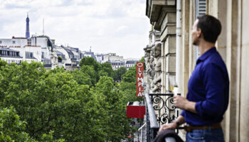 Gay man at Sofitel Le Scribe Paris Opéra, a most-booked luxury hotel in Paris, enjoying the view of the Paris gayborhood from his balcony.