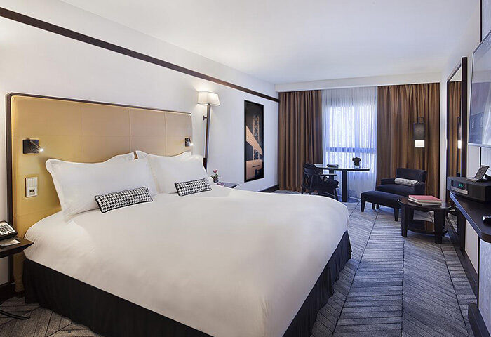 Sofitel Lisbon Liberdade, luxury honeymoon hotel room for gay couples. King bed, desk, chair, and modern decor. Perfect for a romantic getaway.