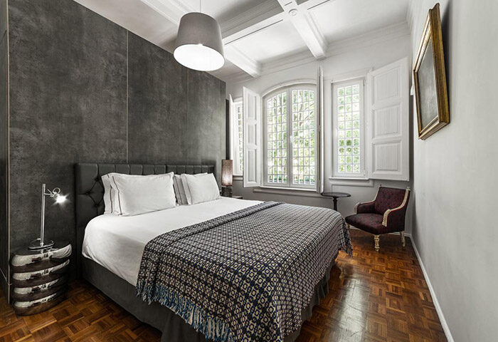 Monte Belvedere Hotel by Shiadu room. Lisbon gayborhood party hotel with bed, windows, chair, and wood floors. Gay travel.