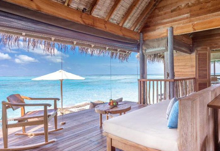 Gili Lankanfushi Maldives villa deck view. Private pool villas at a gay-friendly hotel in the Maldives. Ocean view, rocking chair, and sun umbrella.