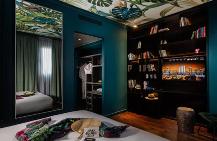Brown Seaside Hotel triple room, Tel Aviv. Gay-friendly hotel room with jungle-themed decor, bookshelf, TV, and closet. Hilton Beach stay.