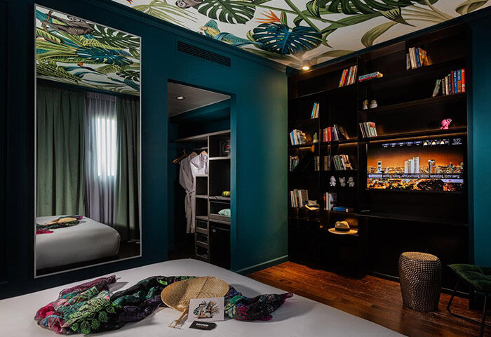 Brown Seaside Hotel triple room, Tel Aviv. Gay-friendly hotel room with jungle-themed decor, bookshelf, TV, and closet. Hilton Beach stay.