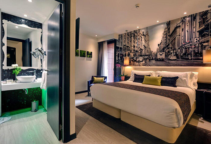 Hotel Indigo Madrid Gran Via room. Upscale gay hotel in Madrid gayborhood. Stylish bathroom, Gran Via mural, king bed. Most booked.