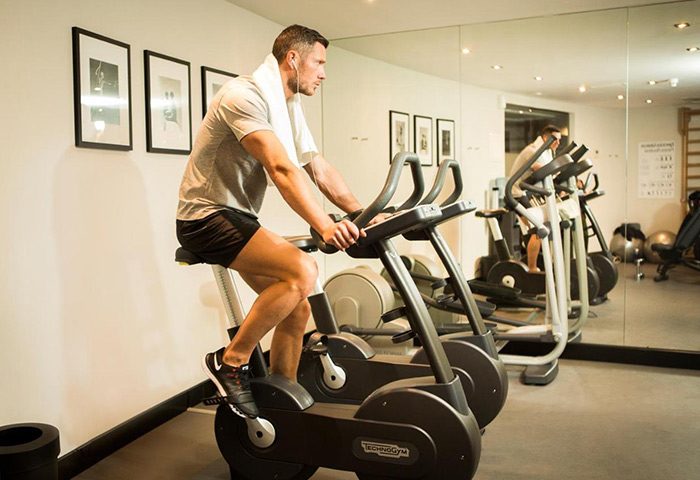 Gay man exercising at The Principal Madrid Hotel gym. Wellness and luxury travel. Most booked hotel this year.