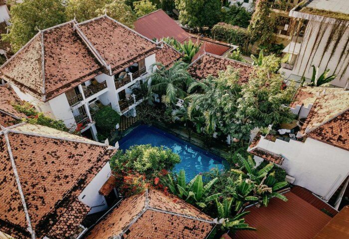 Rambutan Resort Siem Reap aerial view. Charming gay hotel with pool, lush greenery, red tile roofs. Ideal for gay men's travel in Cambodia.