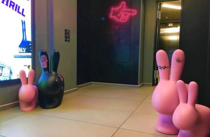 Assembly Hotel London's fun design: Pink & black bunny statues in the lobby. Neon sign points the way. Gay-friendly hotel interior.