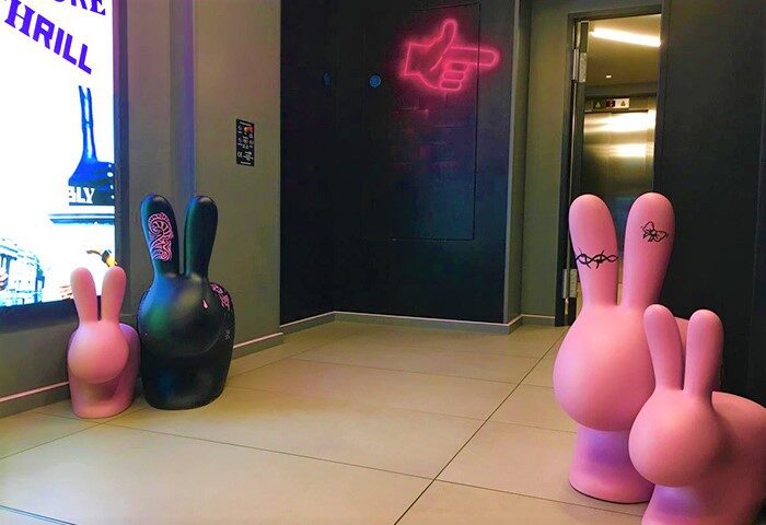 Assembly Hotel London's fun design: Pink & black bunny statues in the lobby. Neon sign points the way. Gay-friendly hotel interior.
