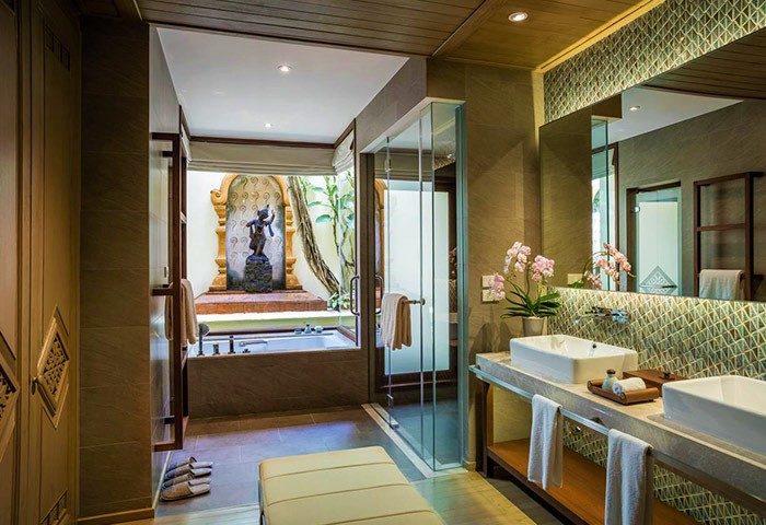 Four Seasons Chiang Mai luxury gay honeymoon hotel bathroom. Bathtub, statue, double sinks, orchids, & glass shower. Thailand resort.