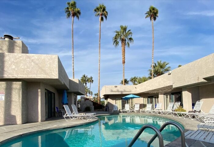 All Worlds Resorts, Palm Springs: Gay men's clothing-optional resort pool. Palm trees, lounge chairs, blue sky. Relaxing vacation spot.