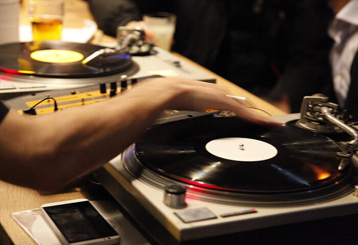 DJ at Les Piaules, a popular gay hostel in Paris. Vinyl record spinning at the bar. Nightlife scene, perfect for gay travelers.