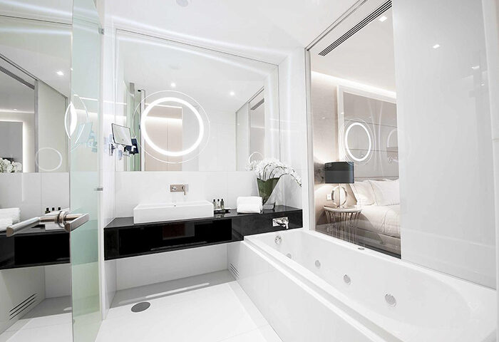 BessaHotel Liberdade bathroom. Modern, all-white design with jacuzzi tub, sink, and mirror. Near Trombeta Bath gay sauna in Lisbon.