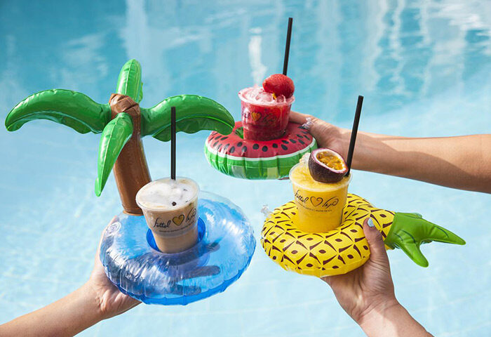 Herods Tel Aviv By The Beach: Drinks with inflatable holders in a pool. Gay couples and friends can enjoy poolside cocktails at this hotel.