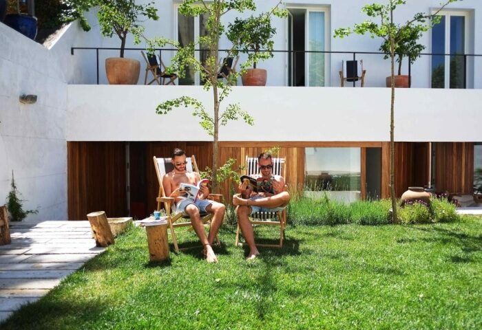 The Late Birds Lisbon gay urban resort: Two men relax in the outdoor swimming pool area, reading magazines. Popular gay hotel in Lisbon.