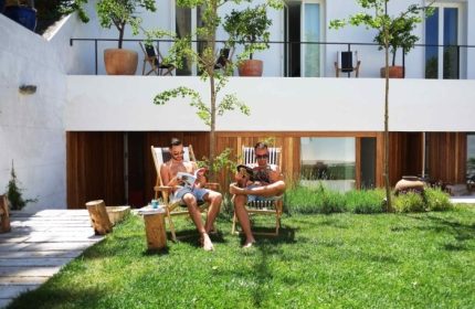 The Late Birds Lisbon gay urban resort: Two men relax in the outdoor swimming pool area, reading magazines. Popular gay hotel in Lisbon.