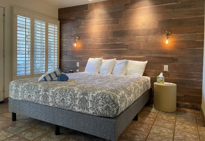 Bedroom at Desert Paradise Resort Hotel, a popular gay men's hotel in Palm Springs. Features a king bed, wood wall, and modern decor.