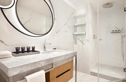 Sheraton Tel Aviv Hotel bathroom. Modern design with marble, round mirror, and glass shower. Popular honeymooners' hotel near Hilton Gay Beach.