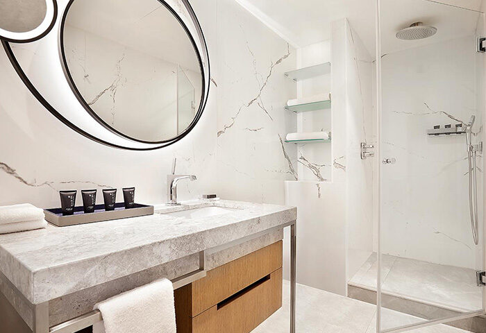 Sheraton Tel Aviv Hotel bathroom. Modern design with marble, round mirror, and glass shower. Popular honeymooners' hotel near Hilton Gay Beach.