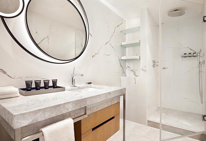 Sheraton Tel Aviv Hotel bathroom. Modern design with marble, round mirror, and glass shower. Popular honeymooners' hotel near Hilton Gay Beach.