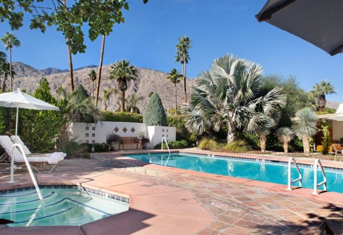 The Hacienda at Warm Sands pool. A luxury gay resort in Palm Springs. Mountains, trees, and lounge chairs visible.